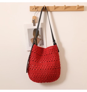 Détail du tissage ajouré rouge et de la bandoulière en cuir noir avec boucle argentée