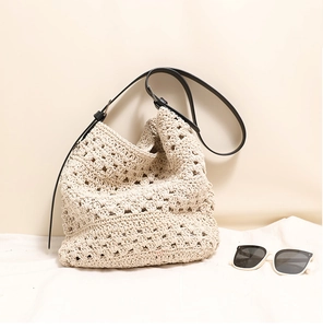 Détail du sac tissé beige à bandoulière en cuir noir avec lunettes de soleil