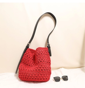 Détail d'un sac au crochet rouge avec bandoulière en cuir noir et boucle argent