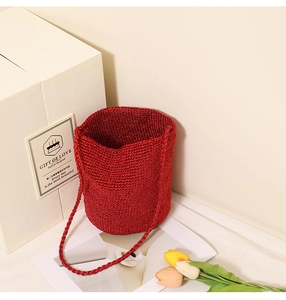 Macro shot of red woven straw bucket bag with matching shoulder strap and texture detail