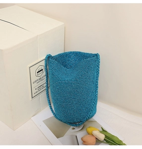 Detailed knit texture of royal blue bucket straw bag on decorative gift box