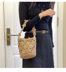 Détail de fleurs au crochet faites main sur un sac seau en paille pour la plage