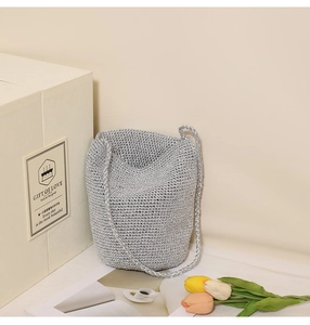 Close-up of silver woven straw bucket bag showing fine hand-crocheted metallic texture
