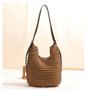 Detailed view of straw hobo bag with brown leather strap and woven texture