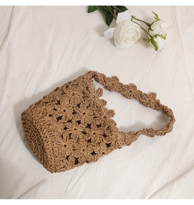Détail du motif de fleurs au crochet fait main sur un sac seau en paille ajourée
