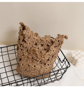 Détails de motifs de fleurs au crochet faits main sur un sac seau de plage en paille