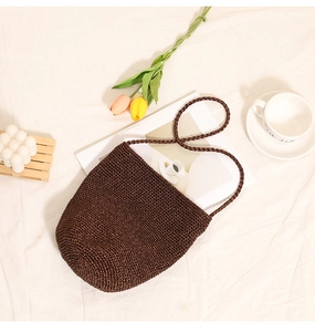 Detail of dark brown handcrafted woven bucket bag on aesthetic minimalist background