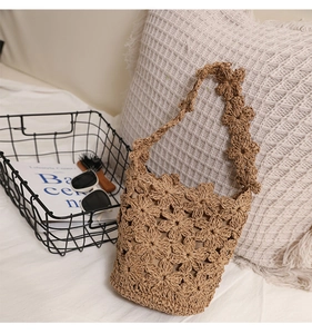 Détail des motifs de fleurs au crochet sur un sac de plage en paille beige tissé