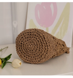 Gros plan de la base tissée en spirale d'un sac seau en paille marron avec fleurs