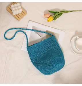 Detailed top view of peacock blue woven bucket bag with matching shoulder strap on linen