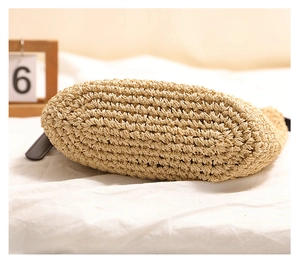 Detailed macro view of the sturdy oval base on the khaki woven straw beach bag