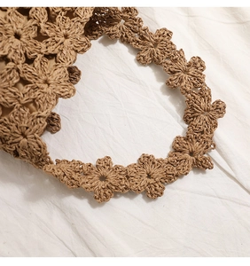 Gros plan sur le motif floral au crochet d'un sac cabas en paille marron naturel