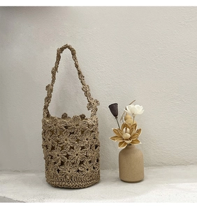 Gros plan sur les motifs floraux crochetés du sac seau en paille beige pour les vacances