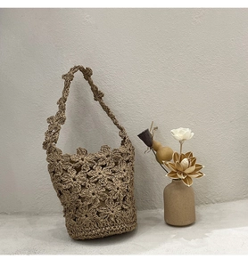 Détails du motif floral au crochet sur un sac seau en paille de style bohème chic