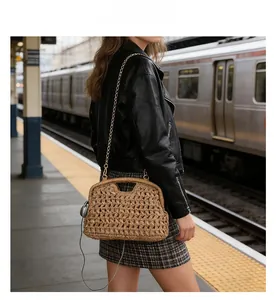 Fashionable straw clutch bag with metal chain strap shown in a modern subway setting
