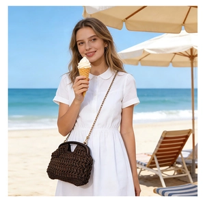 Detail of dark brown woven straw crossbody bag with wood frame against beach background