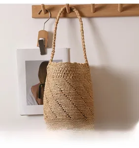 Detail of hand-woven raffia bucket bag with intricate openwork pattern and strap