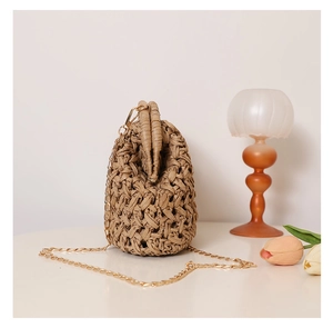 Macro detail of natural woven straw texture and gold metal chain on a retro clutch bag