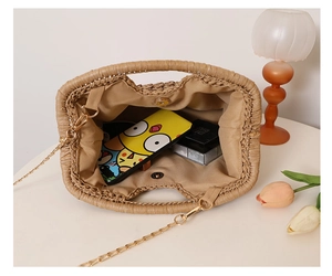 Close-up of woven straw bag interior with magnetic clasp and golden chain strap detail