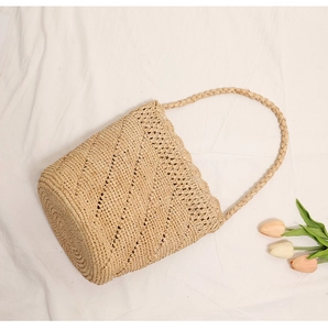 Detailed view of handmade raffia bucket bag with hollow lace edge and braided handle