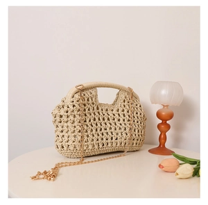 Close-up of beige straw woven bag with hollow knit texture and gold metal chain strap