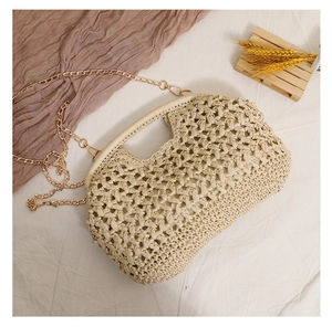 Detail of the woven straw bag featuring hollow texture and detachable gold chain strap