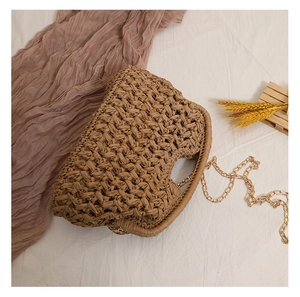 Detailed view of hand-woven straw crossbody bag with elegant gold chain and natural texture