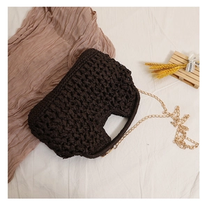 Detail of dark brown woven straw bag with textured grid patterns and gold metal chain strap