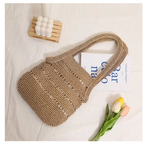 Detailed close-up of khaki woven straw bag showing hollow stripes and knit texture
