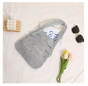 Flat lay of a hollow crochet woven tote bag with silver threads and summer lifestyle props