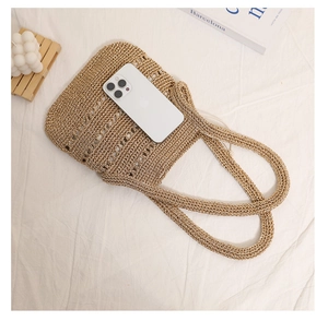 Macro shot of large beige straw woven tote bag showing texture and size with a phone