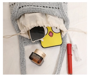 Detail of silver crochet straw bag with drawstring liner showing daily essentials capacity