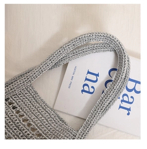 Close-up of metallic silver woven bag featuring hollow crochet pattern and textured handle