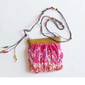 Detail of bohemian mini straw crossbody bag with colorful wooden beads and pink patterns