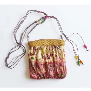 Detail of bohemian woven bag with vintage floral pattern and colorful wooden beads
