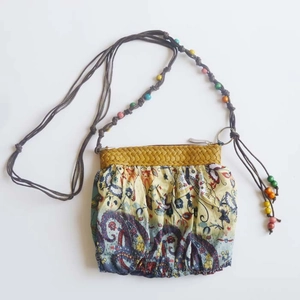 Detail of bohemian cross-body bag featuring paisley print and colorful wooden beads