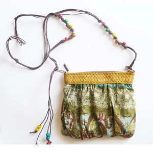 Detail of bohemian floral crossbody bag with yellow woven trim and colorful beaded strap