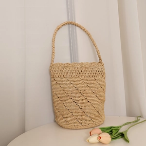 Handwoven raffia bucket bag with hollow wave patterns and scalloped edge for beach vacation