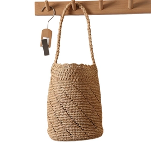 Handwoven raffia bucket bag with scalloped trim and shoulder strap in natural brown