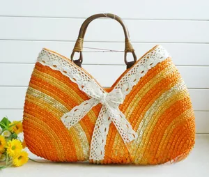 Detail of handmade straw tote featuring orange stripes, white lace trim and wooden handle