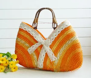 Detail of orange woven straw bag featuring lace trim, bow, and round wooden handles
