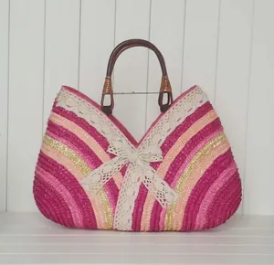 Detail of colorful woven straw bag with pink stripes, lace bow, and wooden ring handles