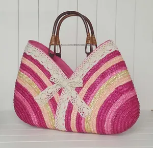 Detail of colorful straw tote bag with white lace bow and round wooden handles