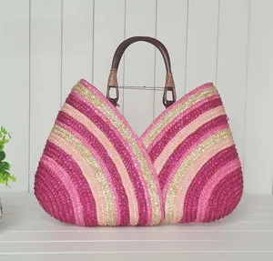 Detail of colorful woven straw bag with pink stripes and round wooden handles for beach