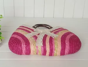 Detail of colorful straw beach bag with white lace bow and round wooden handles
