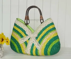 Close-up of woven straw handbag with colorful stripes, lace bow, and wooden handles