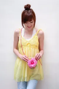 Detailed view of handmade woven straw bag with pink flower accent and crochet yellow top