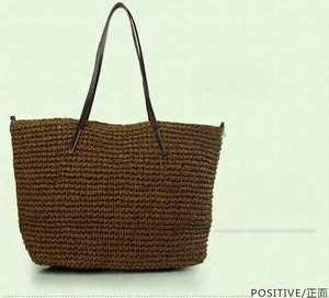 Front view of a brown woven straw tote bag with slim faux leather handles for beach trips