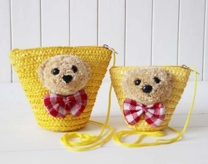 Close-up of woven straw bags featuring cute plush bear accents and checkered bows
