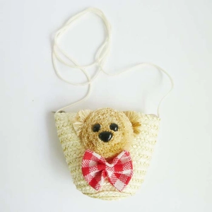 Detail of mini straw crossbody bag featuring a plush bear head and red checkered bow